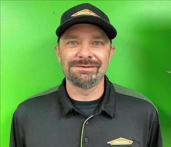 Man wearing a hat and SERVPRO shirt on a green background