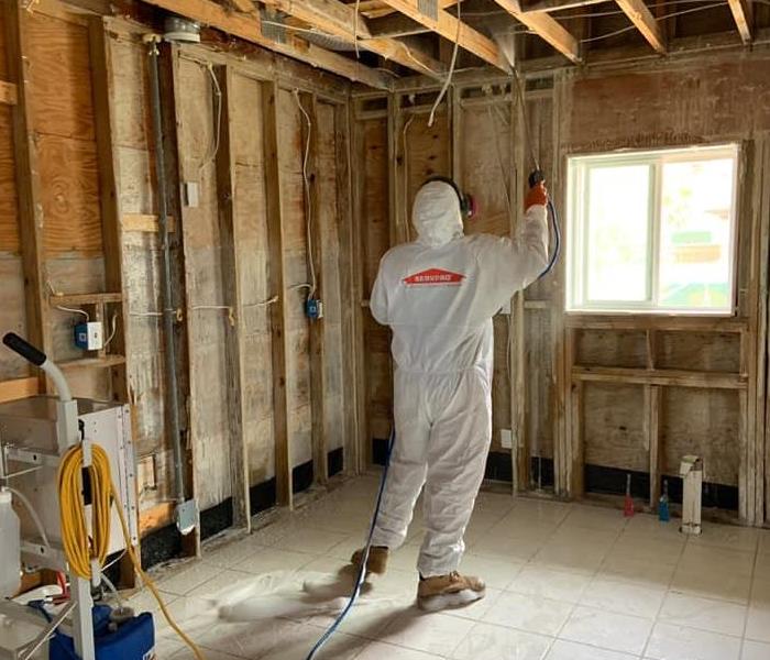 Man in PPE spraying a room in Pensacola, Florida
