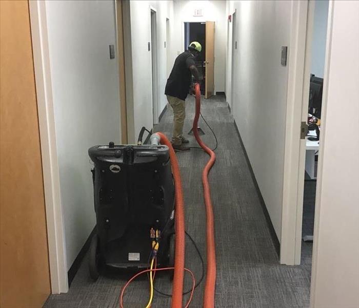 Man extracting water from a carpeted hallway